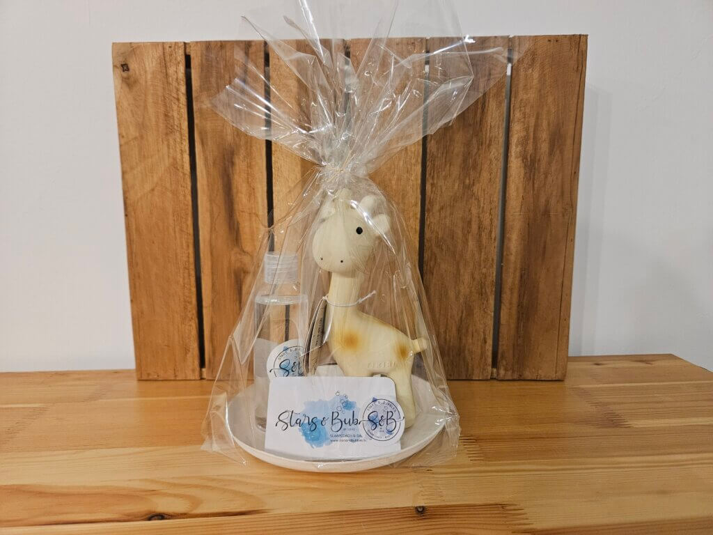 Tikiri set 2 Giraf en een flesje massage-olie mooi ingepakt om kado te geven bij een geboorte of voor een babyshower.